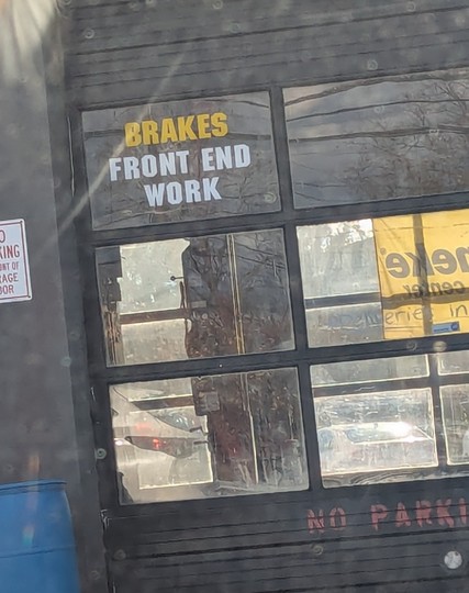 Car mechanic garage door with sign "breaks / front end work"