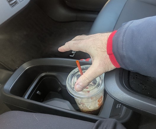 Hand trying to grab drink in cup holder in the 2026 Nissan leaf