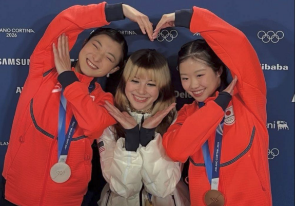 ice skaters who won a medal make one bug heart with all their arms.